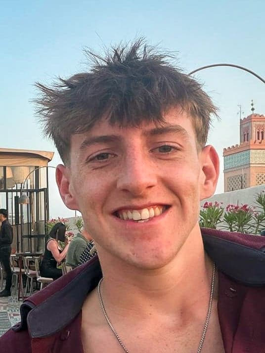 Zac Cope smiling, on a rooftop in the evening sun